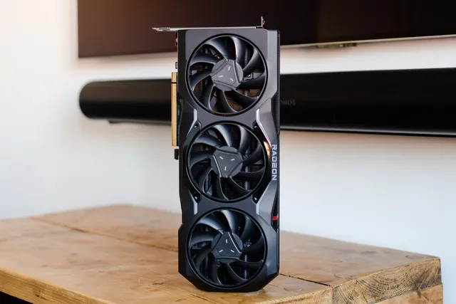 Placa de vídeo AMD Radeon RX 7900 XTX em pé sobre uma bancada de madeira, com três ventoinhas e logotipo Radeon na lateral