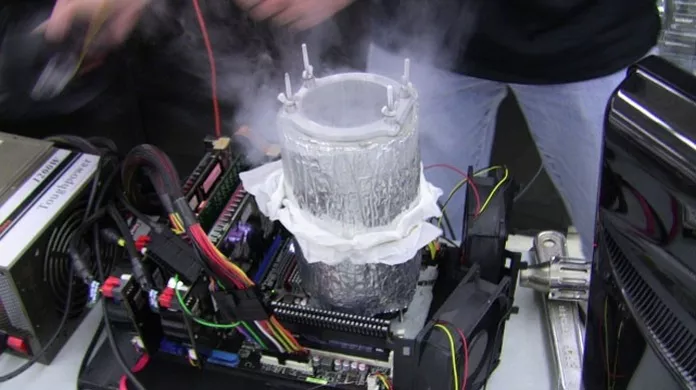 Placa-mãe com cabos coloridos e um cooler de nitrogênio líquido de metal sobre o processador, envolto em vapor frio, usado para overclock extremo