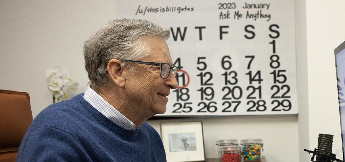 Homem de cabelos grisalhos e óculos sorrindo diante de um calendário de janeiro de 2023 com o texto "Ask Me Anything", ao lado de um microfone e potes de doces…