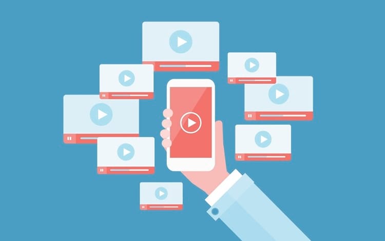 Ilustração de uma mão segurando smartphone com botão de play na tela, cercado por vários cards de vídeo com ícones de reprodução sobre fundo azul