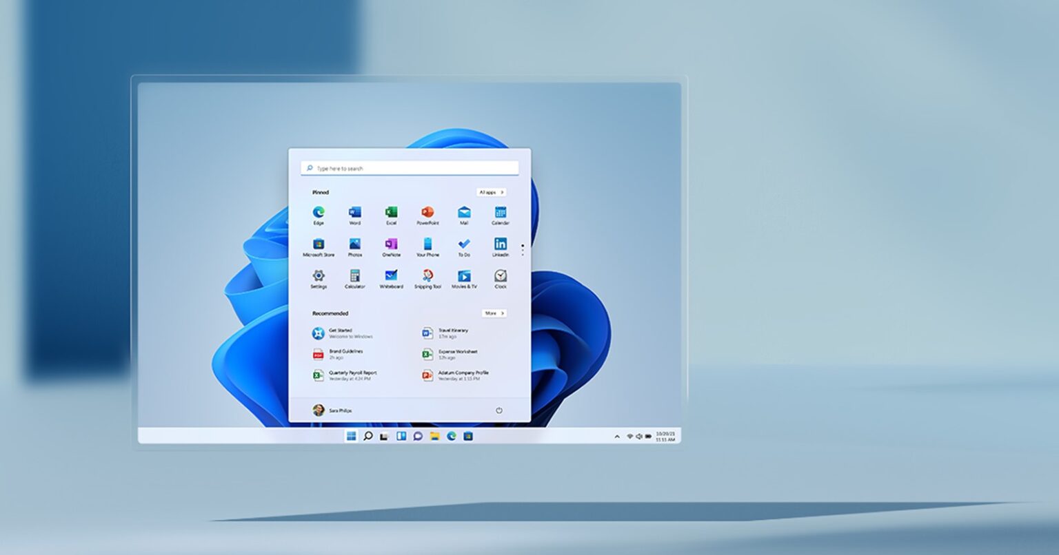 Tela do Windows 11 com o menu Iniciar aberto, mostrando aplicativos fixados e recomendados sobre um fundo azul com desenhos em forma de flor