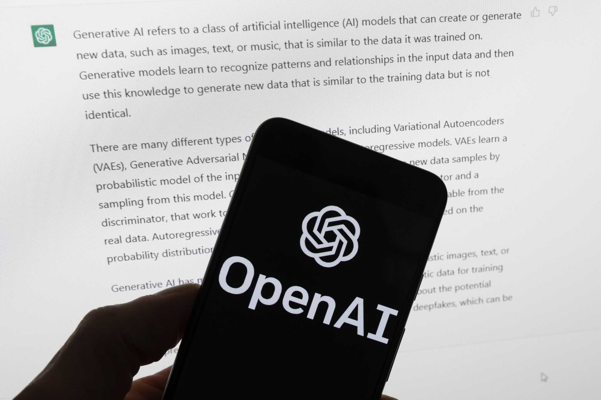Mão segurando smartphone com logo da OpenAI em frente a tela exibindo texto sobre IA generativa do ChatGPT